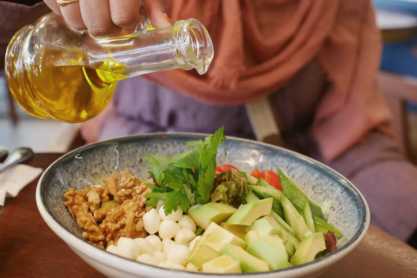 Oil poured from a glass bottle over a bowl of food
