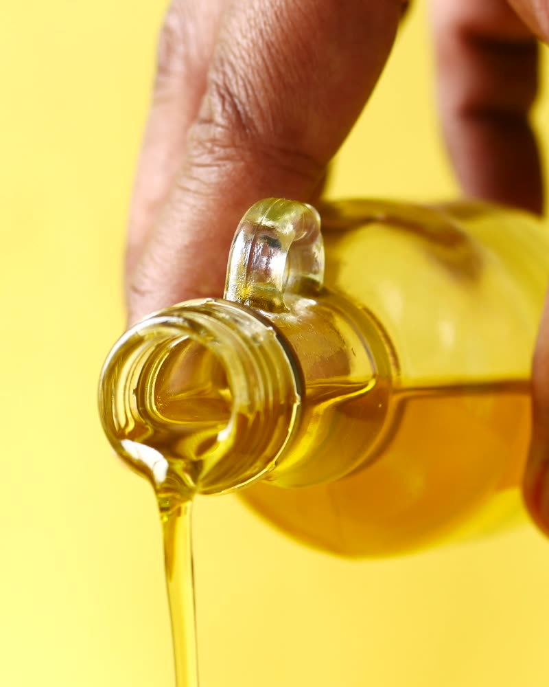 Golden vegetable oil pouring from a glass bottle